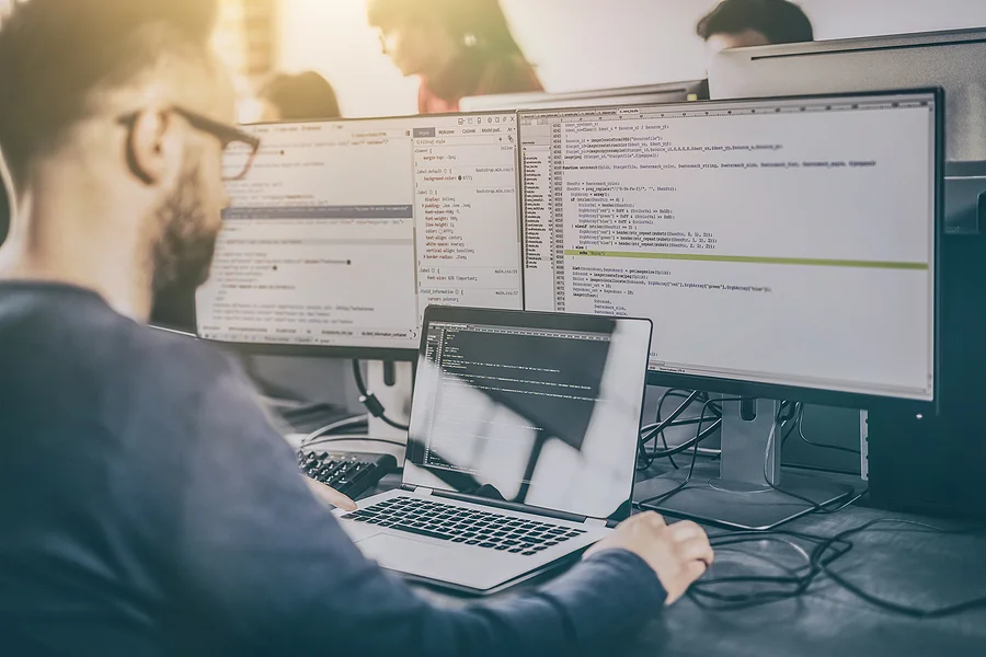 Developer working with code on multiple screens
